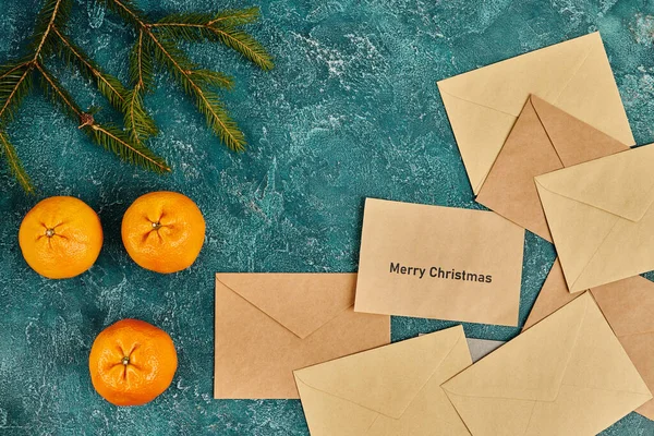 Mandarini e post buste vicino rami di pino su superficie rustica blu, Buon Natale saluto — Foto stock