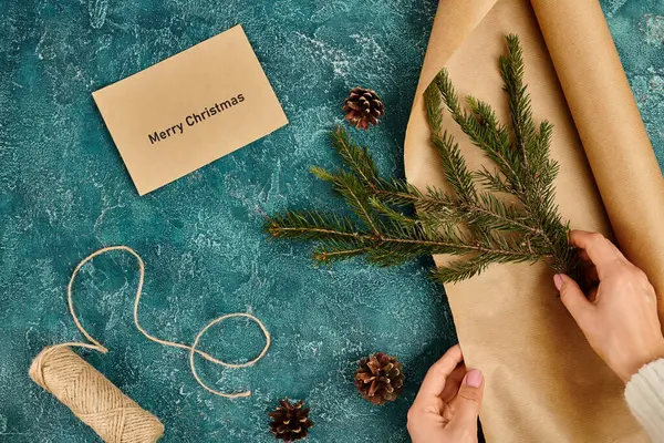 Частковий вид на жінку з сосновою гілкою біля конверта з веселим різдвяним написом та приладдям для їжі — стокове фото