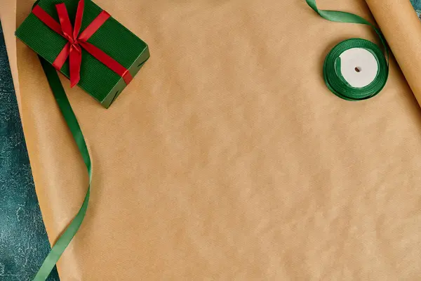Cadeau de Noël bricolage, boîte cadeau verte avec arc rouge près du ruban décoratif sur papier d'emballage artisanal — Photo de stock
