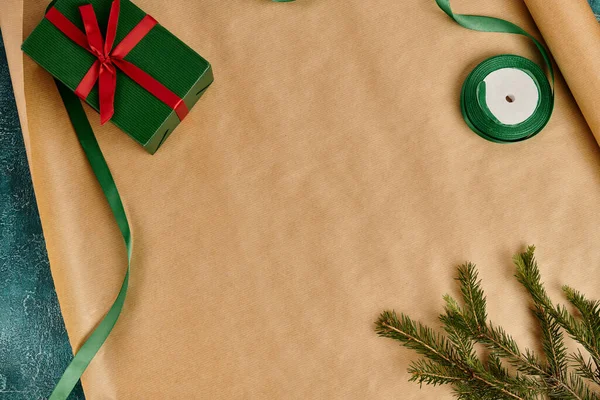 Caja de regalo verde con lazo rojo cerca de la rama de pino y cinta en papel de regalo artesanal, decoración de Navidad - foto de stock