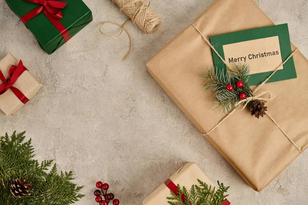 Frohe Weihnachten Grußkarte in der Nähe dekorierter Geschenkboxen auf grauem strukturiertem Hintergrund, Festtagsthema — Stockfoto