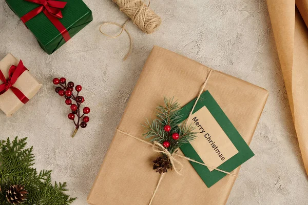 Fondo de Navidad, Tarjeta de felicitación de Feliz Navidad cerca de regalos con ramas de pino y bayas de acebo - foto de stock