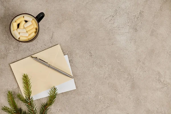 Envelopes pós e caneta perto de ramo de pinho e chocolate quente com marshmallows, pano de fundo de Natal — Fotografia de Stock
