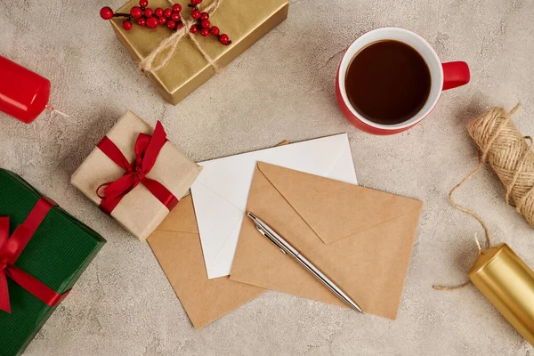 Chocolate quente tradicional perto de envelopes e caixas de presente com velas na textura cinza, Natal — Fotografia de Stock