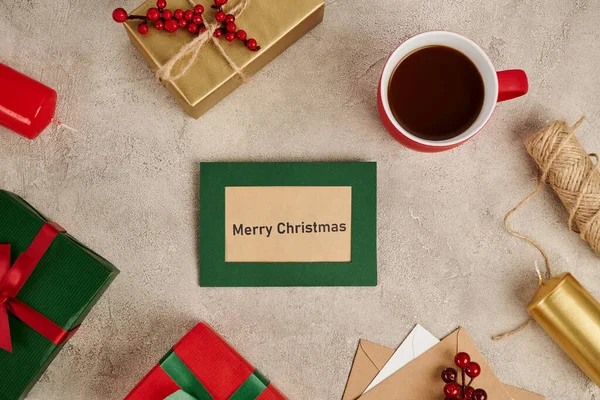 Весела різдвяна листівка біля прикрашених подарункових коробок і кухоль гарячого шоколаду на текстурованій поверхні — стокове фото
