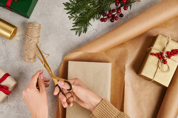 Vista ritagliata della donna con forbici taglio spago vicino scatola regalo e carta artigianale, regali di Natale fai da te — Foto stock