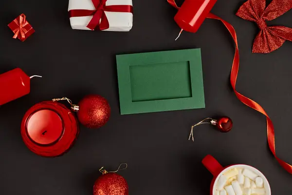 Grüne Grußkarte umgeben von rotem und glänzendem Weihnachtsdekor auf schwarzem Hintergrund, Weihnachten — Stockfoto