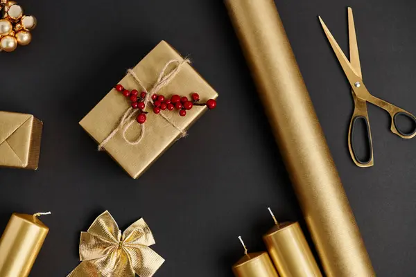 Golden and shiny Christmas objects on black, scissors near rolled paper and candles, diy crafts — Stock Photo