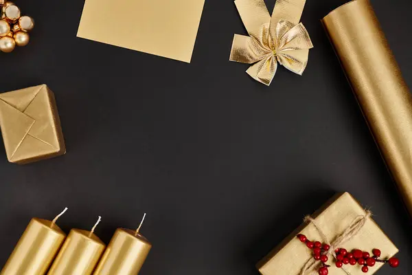 Cornice con oggetti natalizi dorati su nero, scatole regalo con bacche di agrifoglio rosse vicino a candele e fiocco — Foto stock