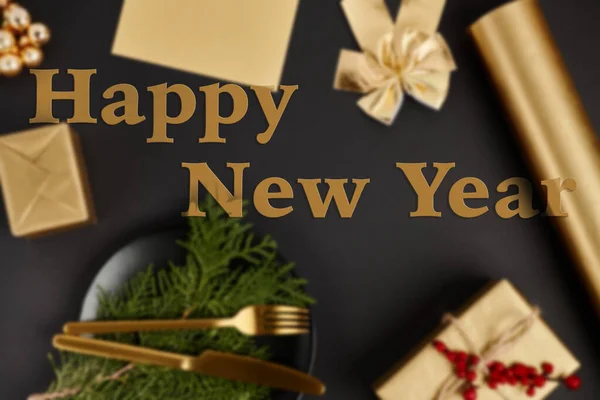 Feliz año nuevo saludo letras sobre fondo borroso de Navidad con objetos de oro en negro - foto de stock