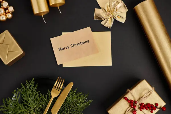 Carte de vœux brillante avec lettrage Joyeux Noël près de couverts dorés et décor festif sur noir — Photo de stock