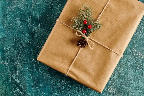 Regalo de Navidad decorado con ramas de pino y bayas de acebo sobre fondo de textura azul - foto de stock