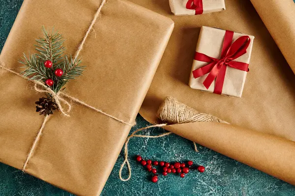 Scatole regalo con nastri rossi e rami di pino con bacche di agrifoglio su carta artigianale, tema natalizio — Foto stock