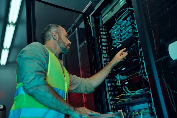 Handsome focused specialist in safety vest with beard working hard on information center — Stock Photo