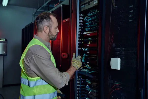 Good looking professional in safety gloves and vest inspecting information storage, data center — Stock Photo