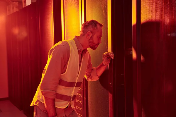 Attractive devoted technician in safety vest and gloves working attentively in data center — Stock Photo