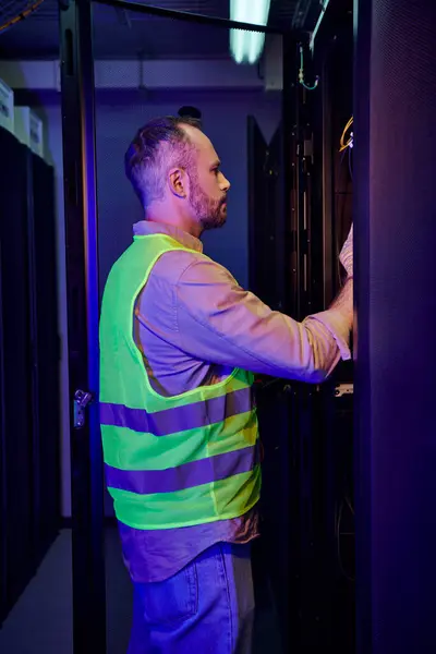 Good looking professional in safety vest inspecting information center attentively, data storage — Stock Photo