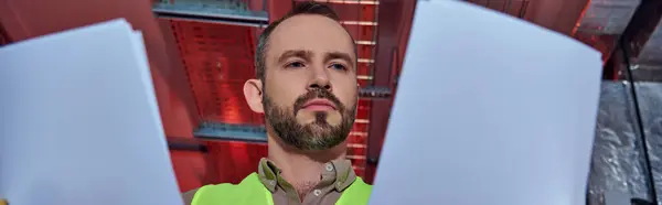 Especialista bonito concentrado em colete de segurança olhando para seus papéis no trabalho, data center, banner — Fotografia de Stock