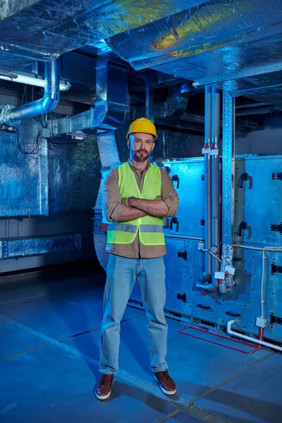 Cheerful handsome specialist with helmet posing with arms crossed on chest and looking at camera — Stock Photo