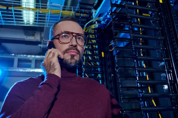Bello concentrato data center specialista in dolcevita con occhiali parlare per telefono durante il suo lavoro — Foto stock