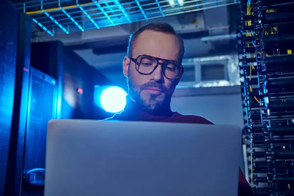 Concentré beau professionnel à col roulé avec des lunettes et de la barbe en regardant son ordinateur portable, des données — Photo de stock