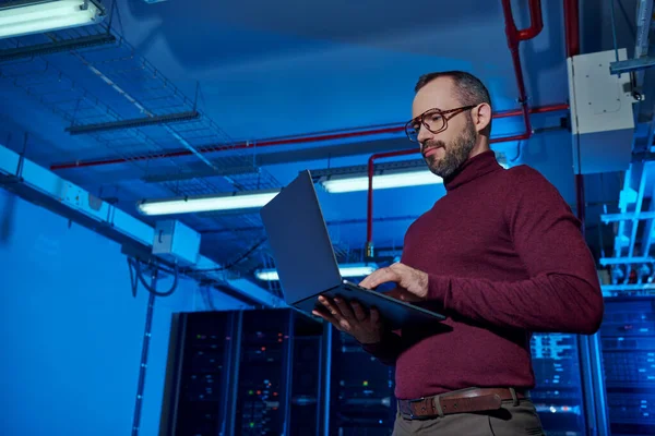 Allegro specialista di data center pensoso in dolcevita che lavora duramente sul suo computer portatile, informazioni — Foto stock