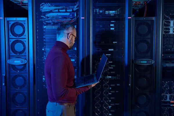 Handsome focused data center specialist in turtleneck with glasses working hard on his laptop — Stock Photo