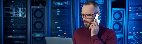 Devoted specialist in turtleneck talking by phone and looking at his laptop, data center, banner — Stock Photo