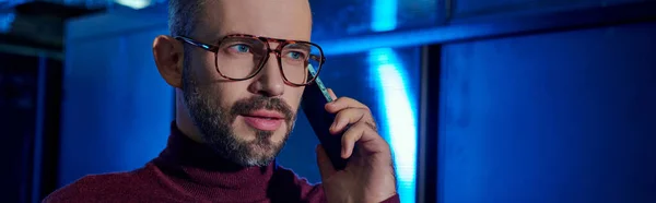 Pensive data center specialist with beard and glasses in turtleneck talking by phone at work, banner — Stock Photo
