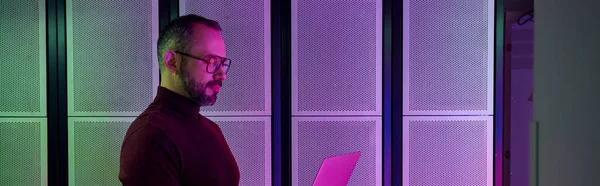Alegre profissional em gola alta com óculos e barba trabalhando no laptop, data center, banner — Fotografia de Stock