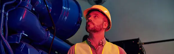 Handsome pensive technician with beard and helmet in safety vest looking away during his work — Stock Photo