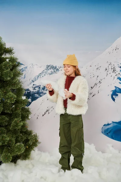 Cheerful preteen girl in warm stylish outfit with beanie hat with mountain backdrop, fashion concept — Stock Photo