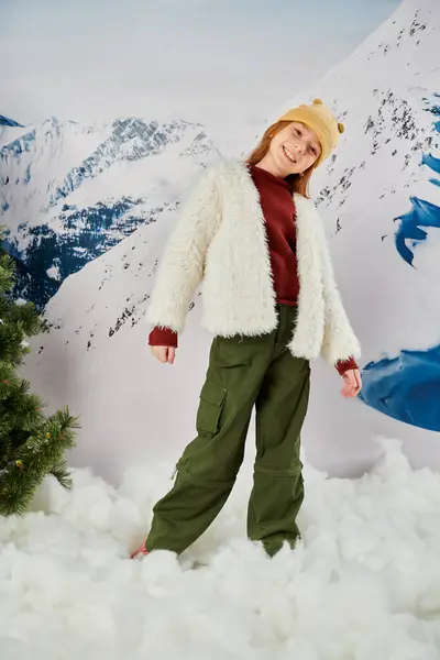 Vertikale Aufnahme eines hübschen Mädchens in warmer, stylischer Kleidung, das in die Kamera lächelt, mit einem Berg im Hintergrund — Stockfoto
