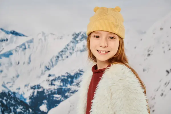 Ritratto di elegante bambina in caldo vestito alla moda sorridente alla fotocamera con sfondo di montagna — Foto stock