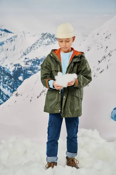 Vertical shot of little boy with  snow in hands wearing stylish warm outfit, fashion — Stock Photo