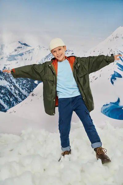 Jolly preteen boy in stylish winter outfit with arms aside and smiling cheerfully at camera, fashion — Stock Photo