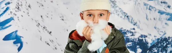 Menino bonito em chapéu de gorro com neve nas mãos perto do rosto, olhando para a câmera, conceito de moda, banner — Fotografia de Stock