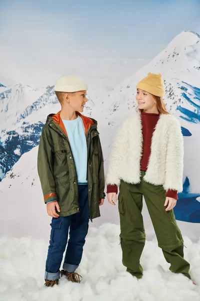 Vertical shot of preadolescent boy and girl in winter attire smiling at each other, fashion concept — Stock Photo