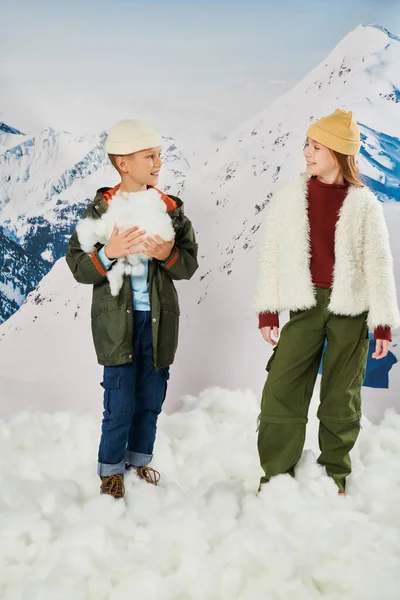 Vertical shot of cute friends in stylish outfits holding snow and looking at each other, fashion — Stock Photo