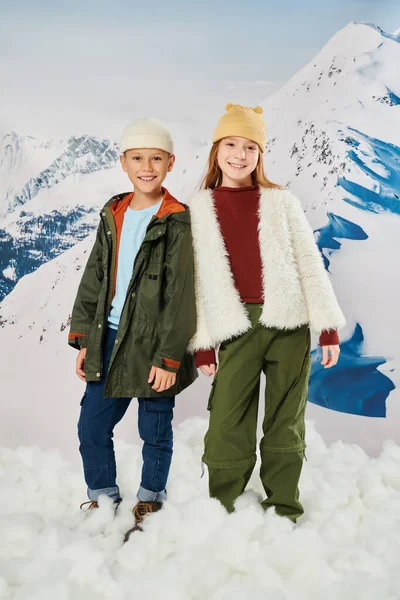 Vertical shot of joyous little children in winter stylish attire smiling joyfully at camera, fashion — Stock Photo
