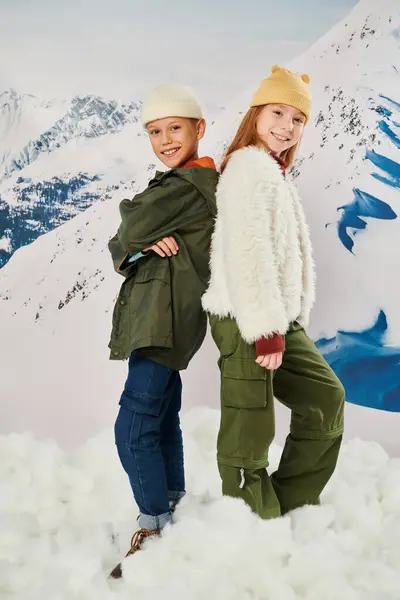 Vertikale Aufnahme von netten Freunden in stylischer Winterbekleidung, die Rücken an Rücken posieren, in die Kamera lächeln, Mode — Stockfoto