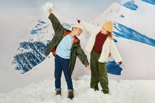 Stylish friends in warm attire posing in motion, holding hands like a plane fly, fashion concept — Stock Photo