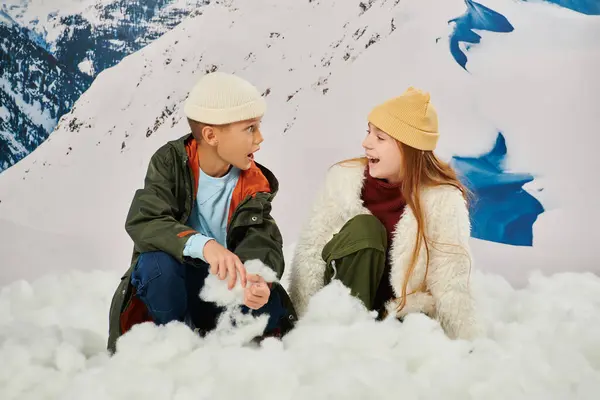 Здивовані щасливі друзі в теплих стильних вбраннях, сидячи на снігу і дивлячись один на одного, мода — стокове фото