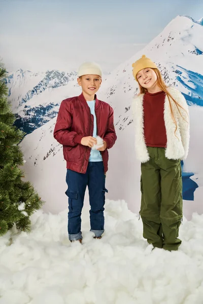 Preadolescent adorable children in winter attire standing on snow smiling at camera, fashion concept — Stock Photo