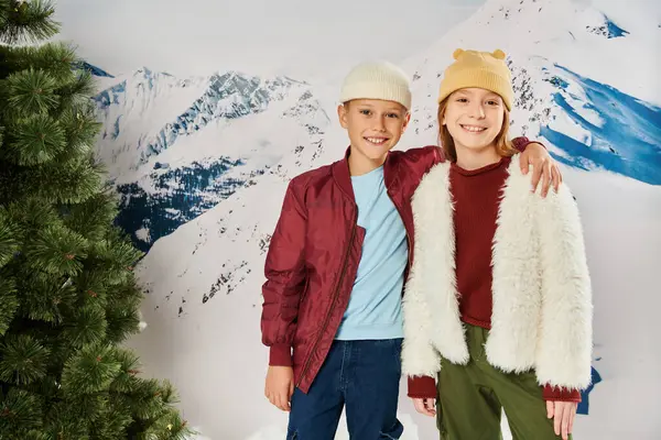 Petit garçon avec la main sur l'épaule de la fille souriant à la caméra, tenue d'hiver élégante, concept de mode — Photo de stock