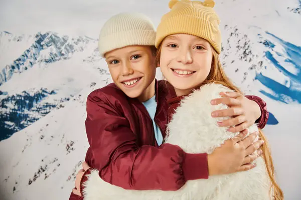 Allegri bambini preadolescenti in eleganti cappelli beanie che abbracciano calorosamente e sorridono alla macchina fotografica, alla moda — Foto stock