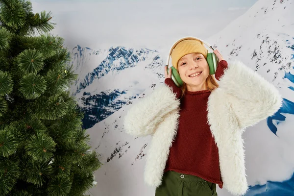 Fröhliches stilvolles Mädchen in warmer Kleidung genießt Musik auf dem Headset und lächelt fröhlich, Modekonzept — Stockfoto