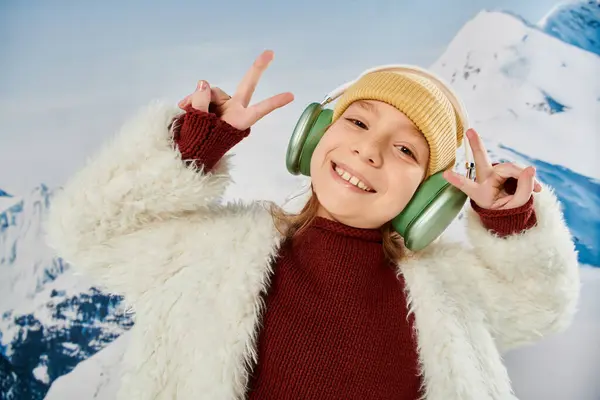 Portrait of preteen girl with headset smiling joyfully at camera showing peace sign, fashion concept — Stock Photo