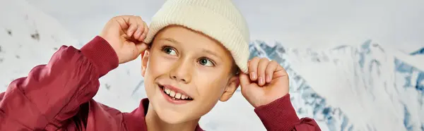Niño alegre con un atuendo elegante que se pone su sombrero de gorro de moda, concepto de moda, bandera - foto de stock