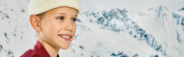 Kleiner netter Junge mit Mütze, der mit schneebedecktem Berg vor der Kulisse wegschaut, Modekonzept, Banner — Stockfoto